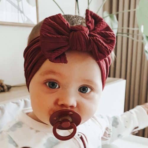 Baby with burgundy headband and pacifier